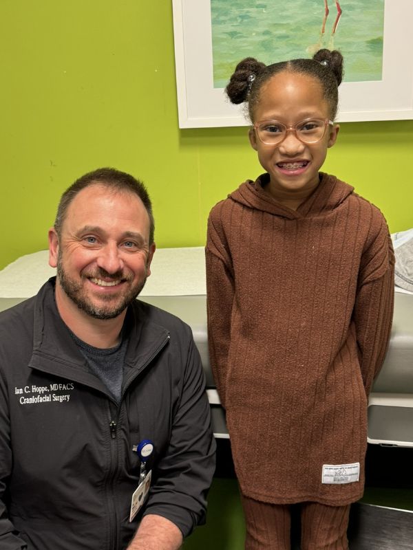 A girl, standing with her doctor, who has been treated for cleft palate.